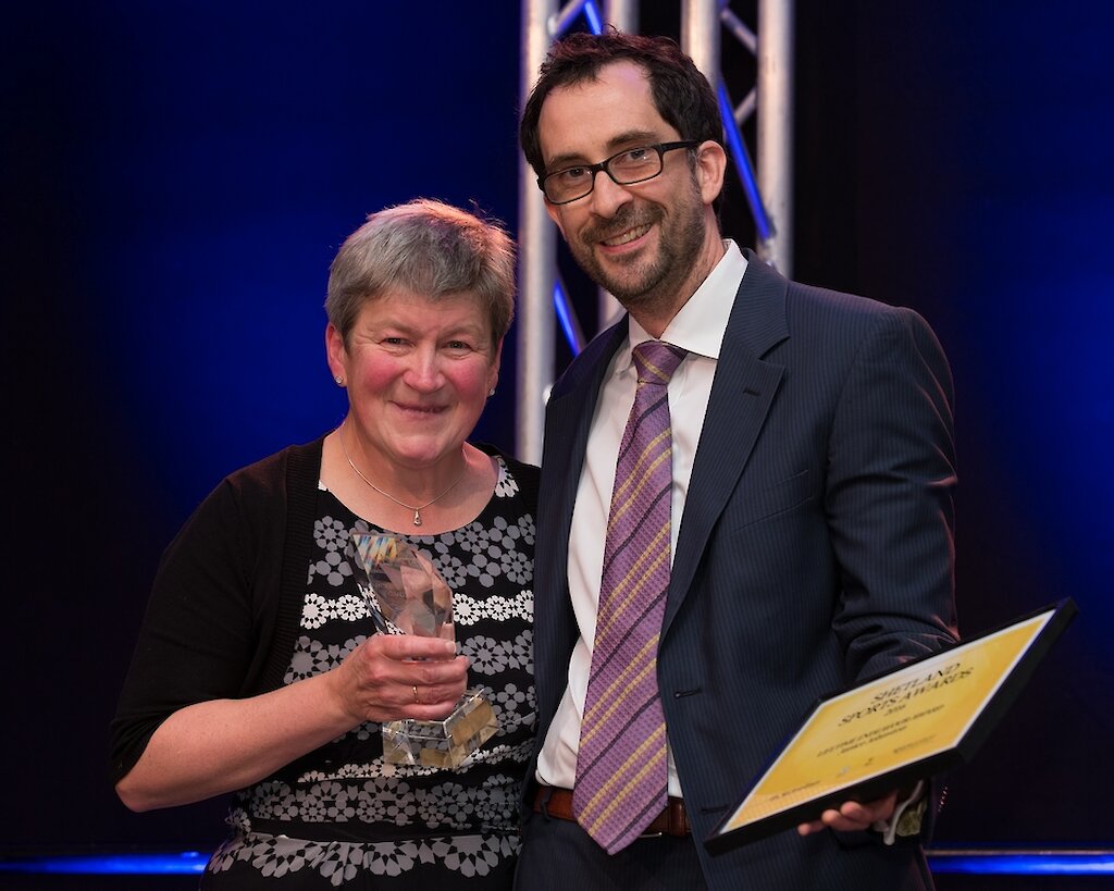 Janice Johnston after being presented with the Lifetime Endeavour Award by SIC councillor George Smith, pictured with Shetland Times editor Adam Civico. Photo: Kevin Jones.