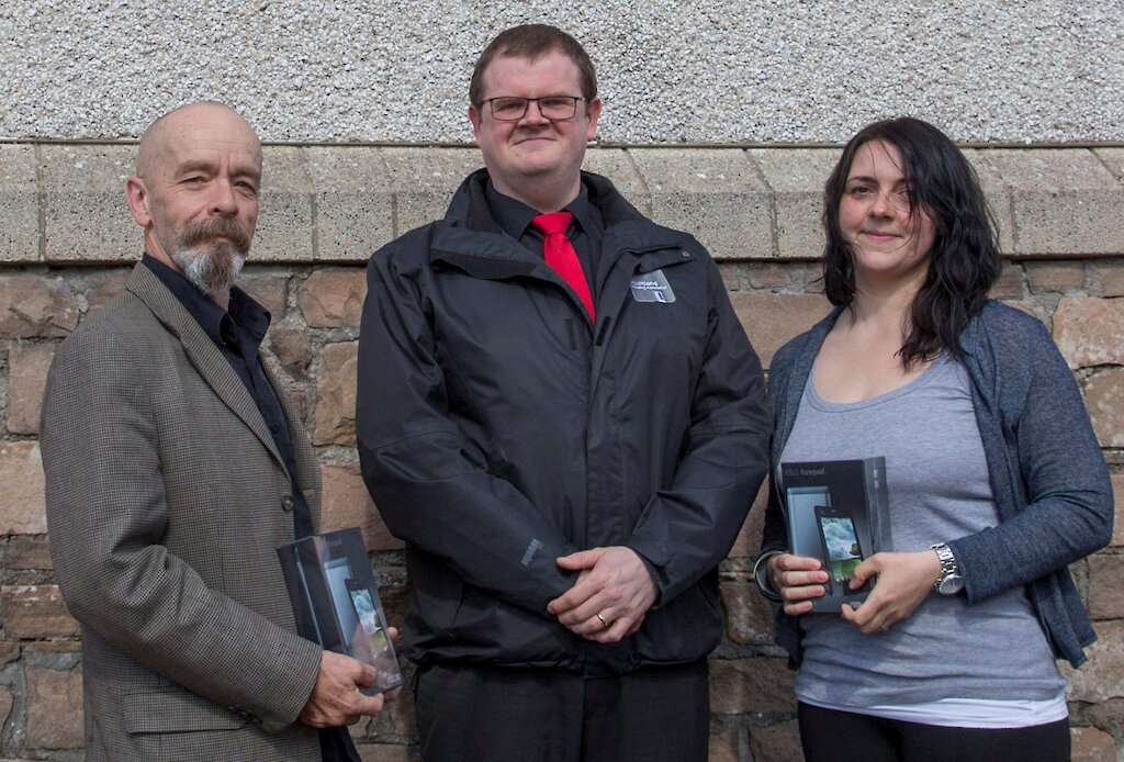 SRT Chairman presents Asus Fonepads to Gary Cleaver from Unst and Fiona Sinclair from Walls, who won the prizes in the draw for participants of the non-user survey.